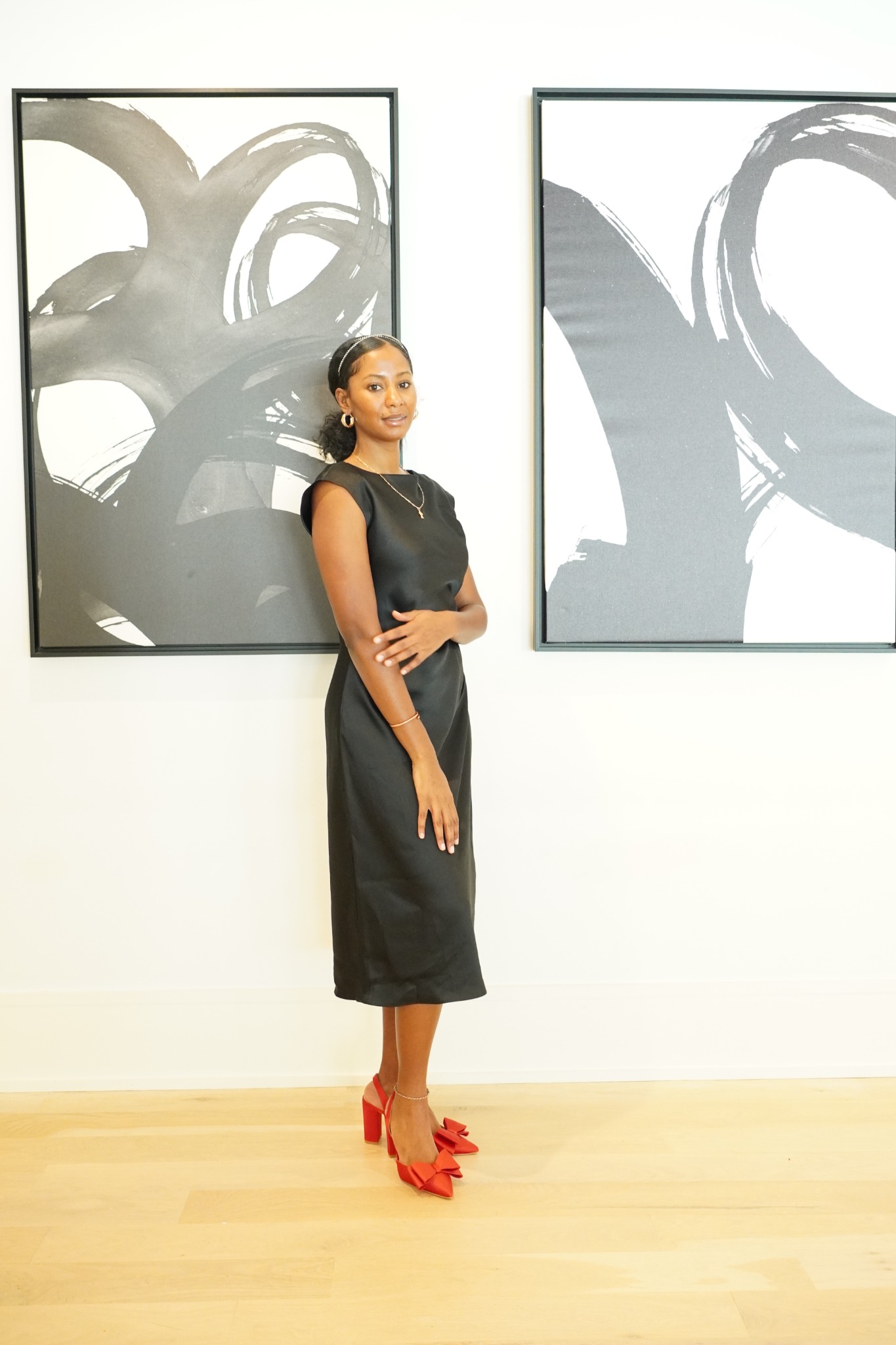 Kevia standing in a black dress beside framed artwork